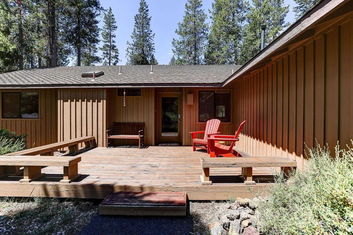Red Adirondack chairs sit on a wooden deck surrounded by trees, evoking a sense of relaxation and connection with nature. The deck setting is inviting, ideal for unwinding or socializing after a day of activities.