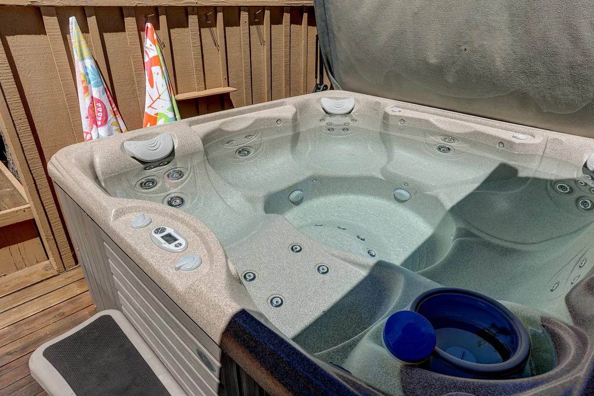 A private hot tub sits on a wooden deck, with towels ready for use and plenty of open space for relaxation or socializing. The setup is perfect for enjoying the outdoors year-round, whether soaking in the morning or under the stars.