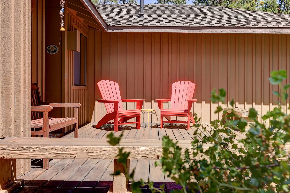 A cozy wooden deck accented by red Adirondack chairs nestled among green foliage, ideal for relaxing and enjoying the outdoors after a day of adventure.